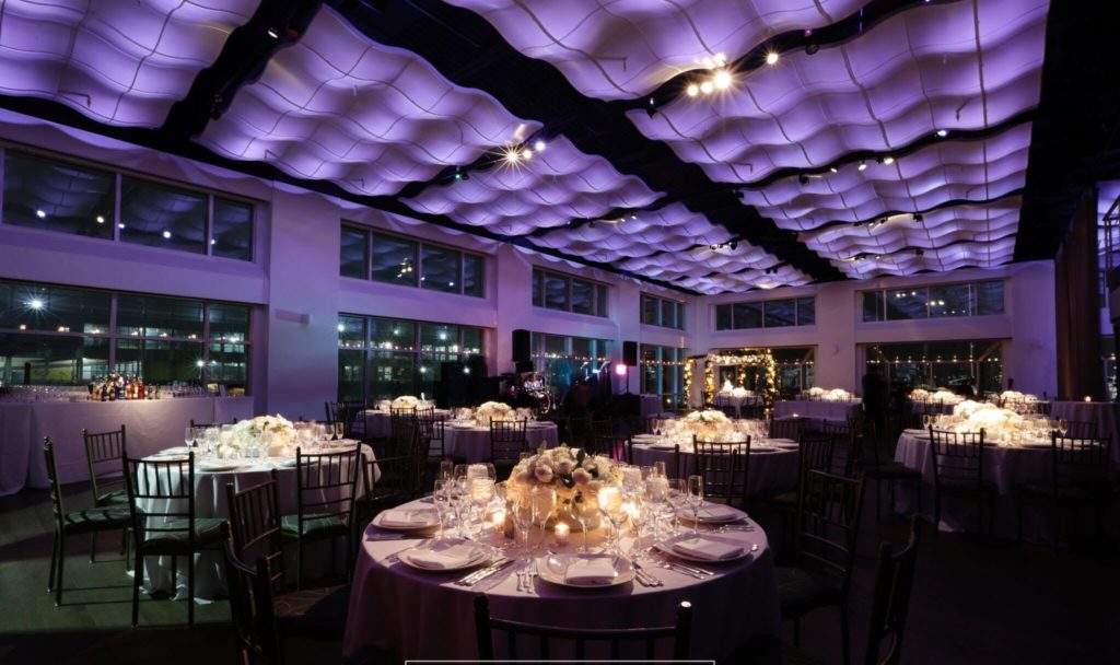 Dinner rounds with candles and white florals under purple lighting at Current, Chelsea Piers