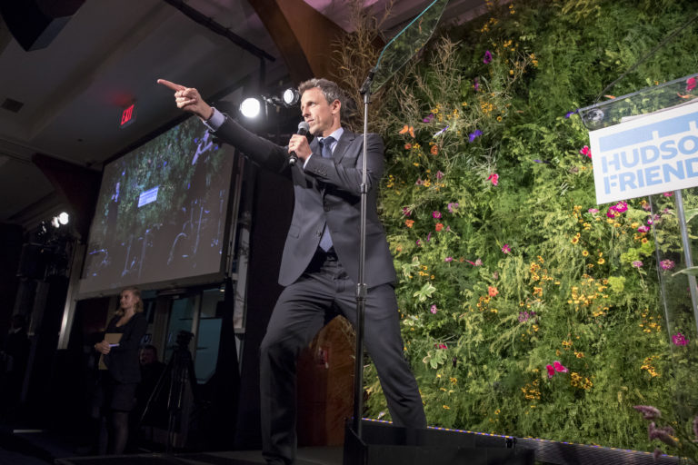 Seth Meyers is on stage pointing to something.