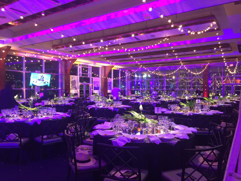 Pier Sixty set in round tables, screens displaying presentation, water views