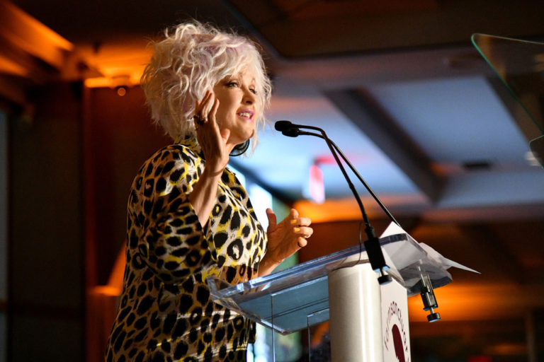 Woman in leopard print shirt speaks at podium
