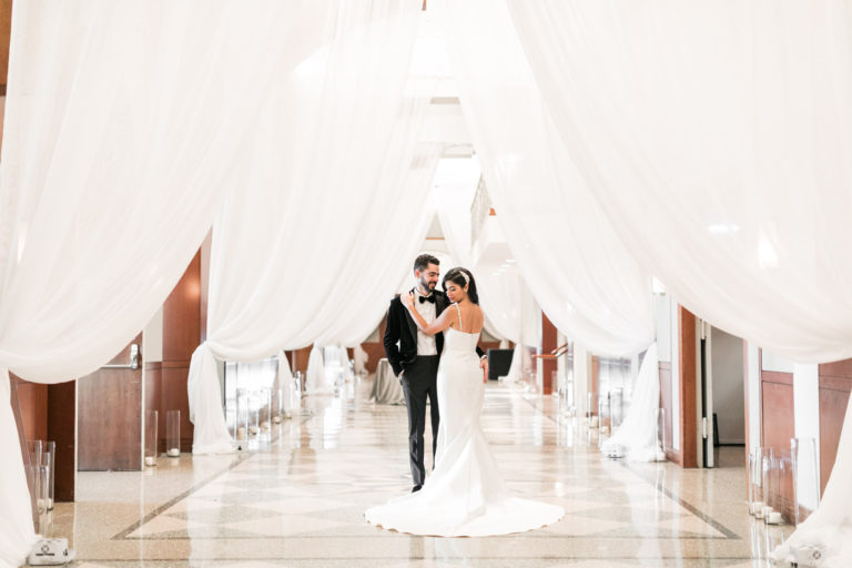 Young couple embrace under rows of drapes.