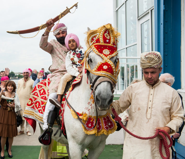 Man and child wearing traditional Indian garb on horseback
