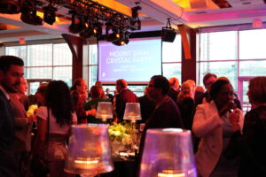 Guests seated at their tables surrounded by windows for the Mount Sinai Crystal Party at Pier Sixty