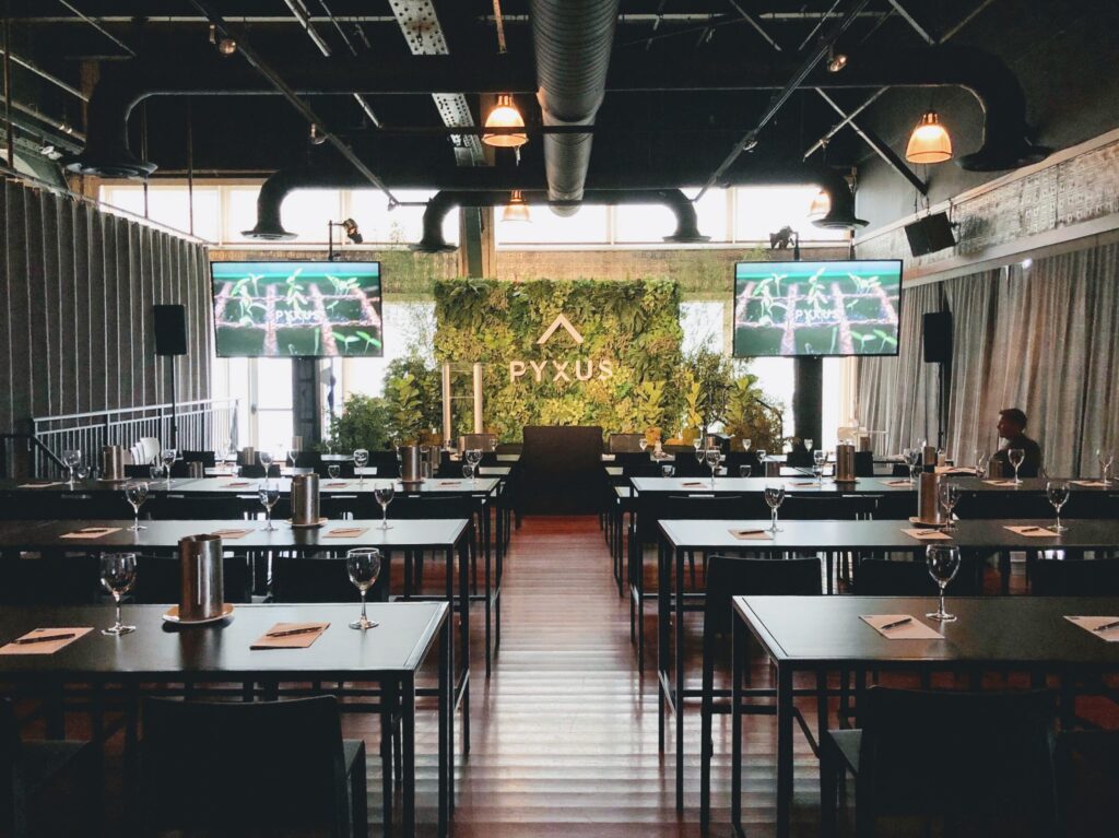 Meeting set at long tables facing a greenery stage wall at The Lighthouse, Chelsea Piers