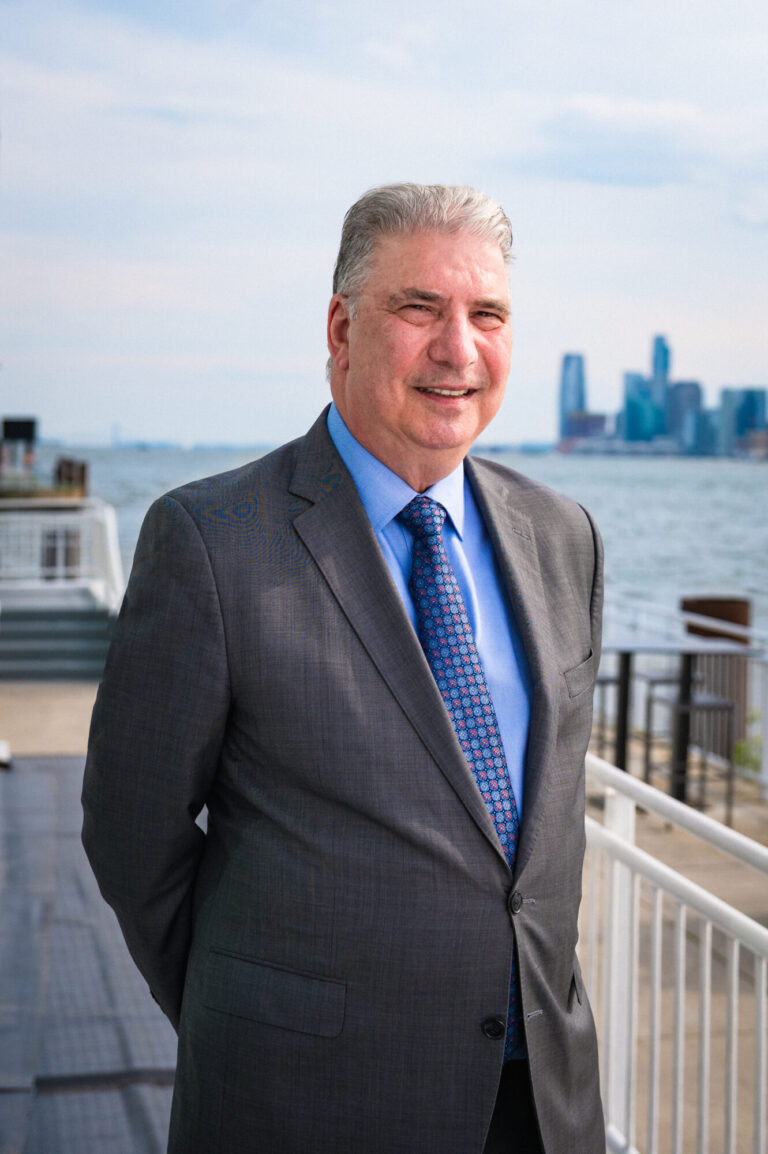 David Najemian smiling by the waterfront with the Manhattan skyline in the background at The Pier Sixty Collection